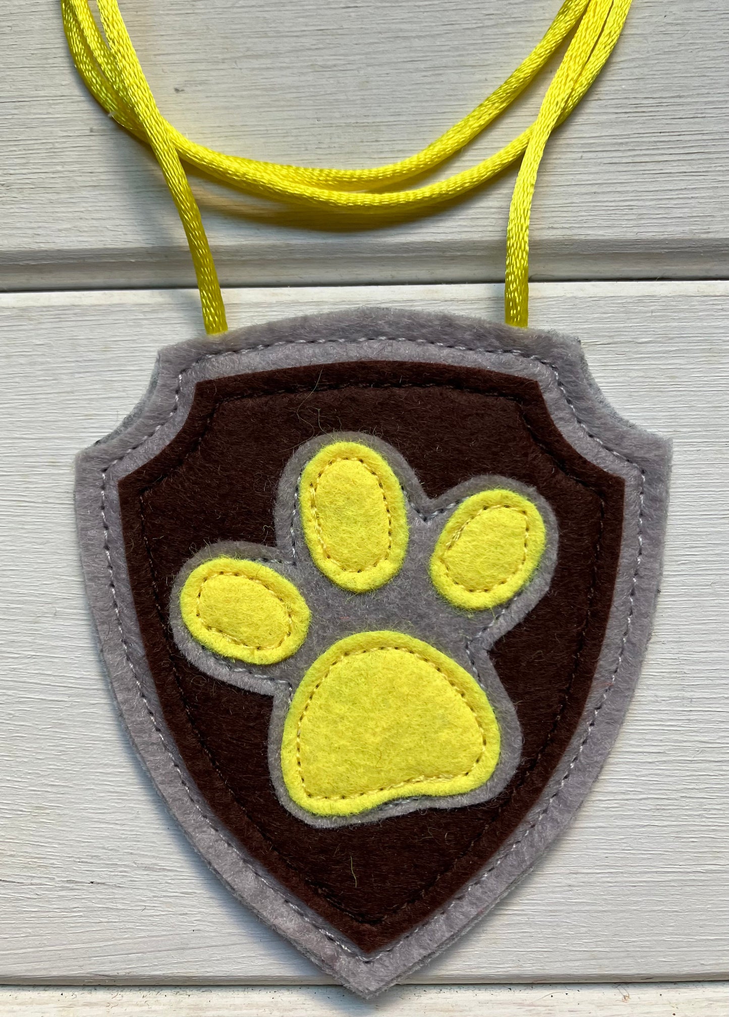 handmadeshield-shaped  felt badge with hanging string representing a paw patrol character