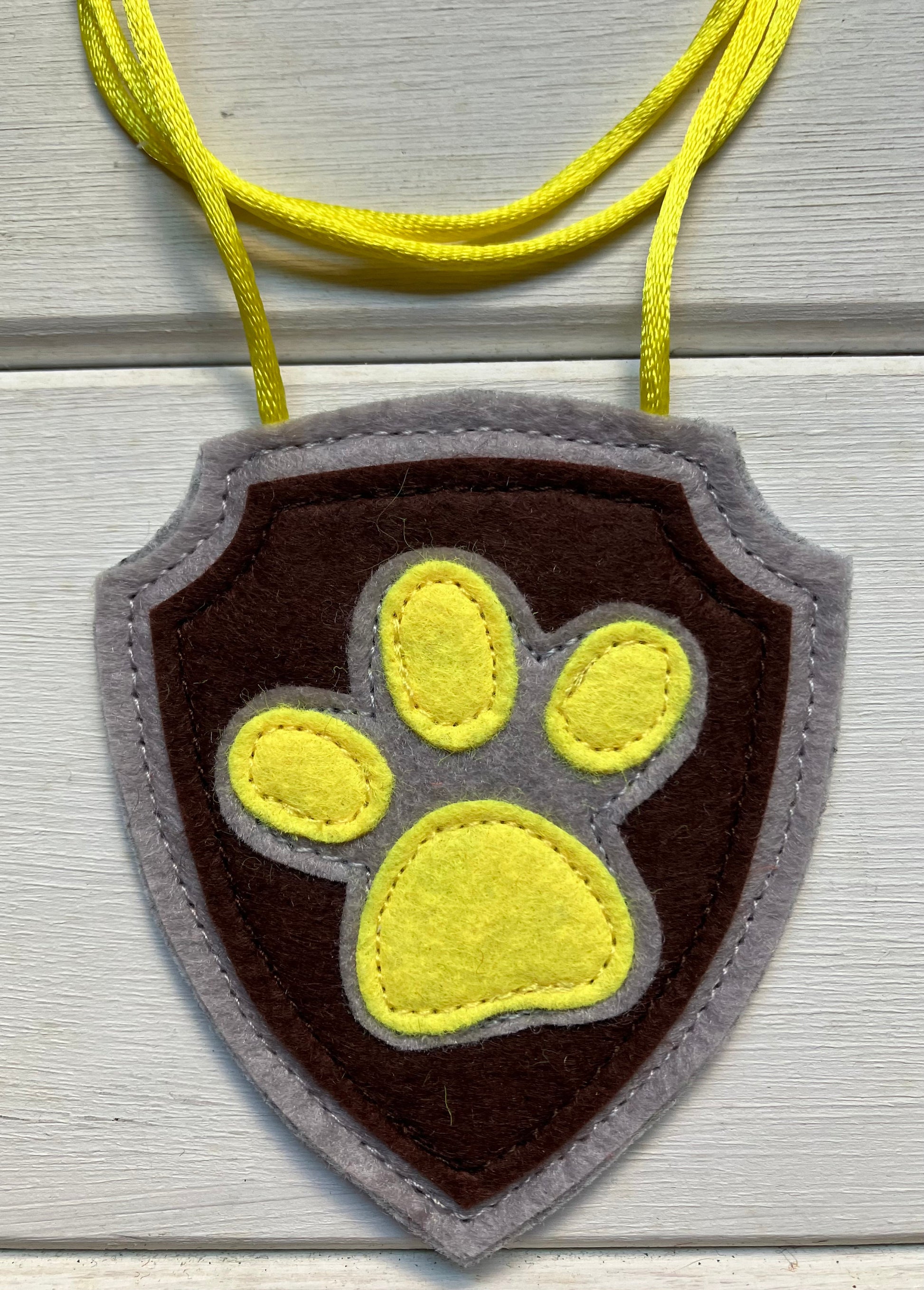 handmadeshield-shaped  felt badge with hanging string representing a paw patrol character