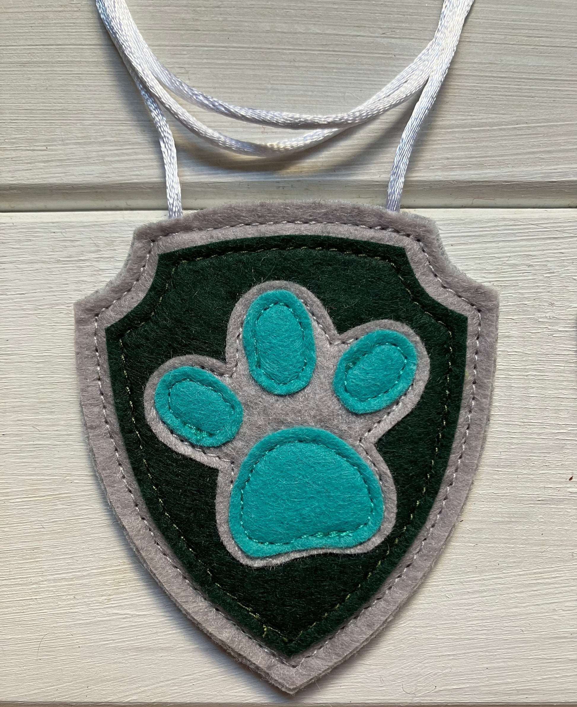 handmadeshield-shaped  felt badge with hanging string representing a paw patrol character