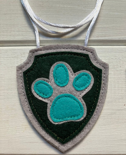 handmadeshield-shaped  felt badge with hanging string representing a paw patrol character