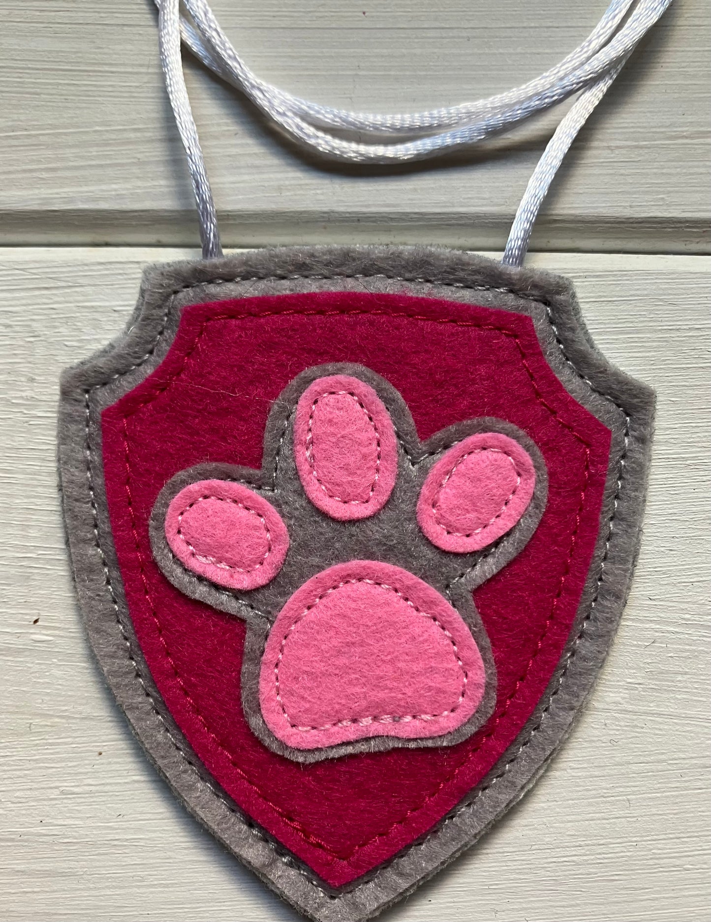 handmadeshield-shaped  felt badge with hanging string representing a paw patrol character