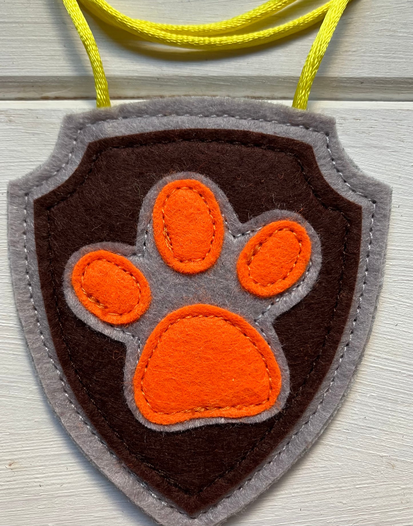 handmadeshield-shaped  felt badge with hanging string representing a paw patrol character