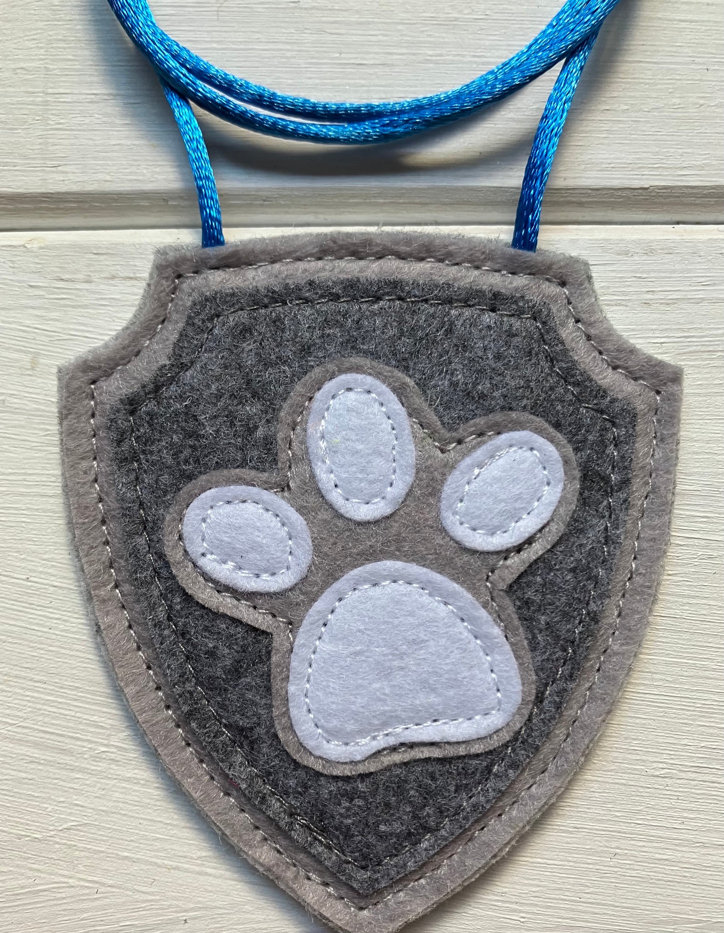 handmadeshield-shaped  felt badge with hanging string representing a paw patrol character