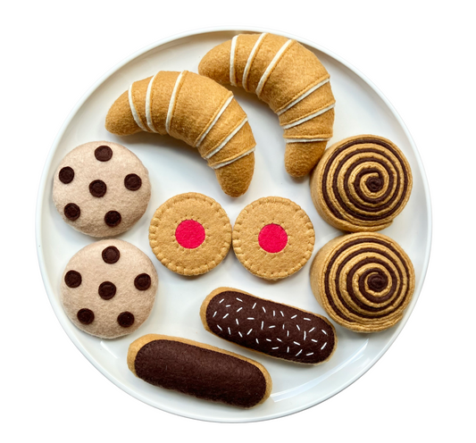 handmade felt play food Croissant  Chocolate Chip Cookie Marmalade Cookie  Cinamon Roll and Eclairs presented on a white plate