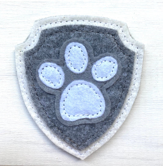Shield-shaped patch with paw print design on a white background
