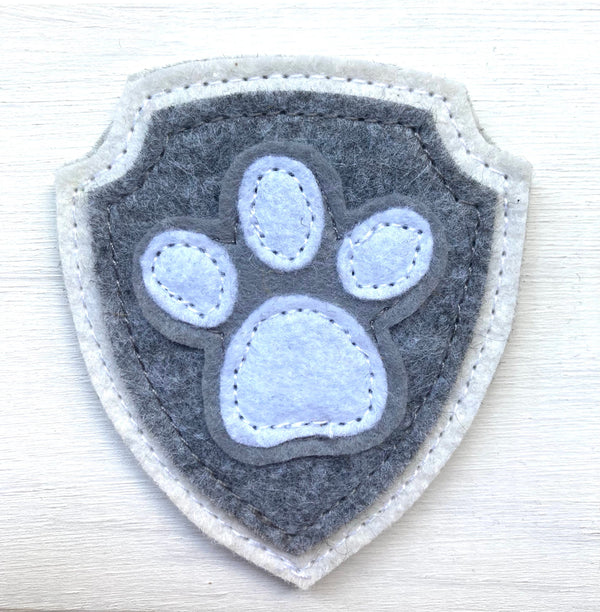 Shield-shaped patch with paw print design on a white background
