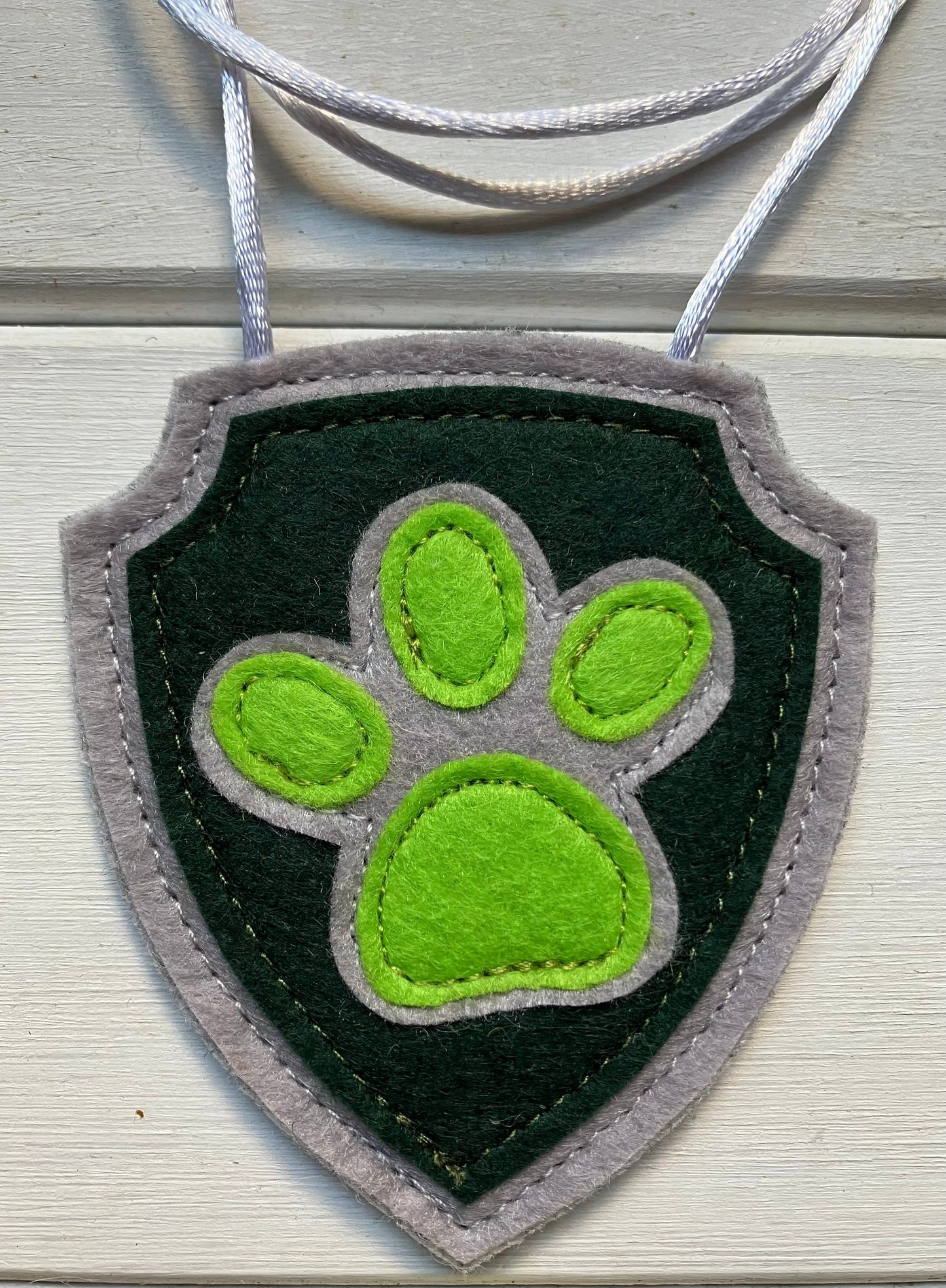 handmadeshield-shaped  felt badge with hanging string representing a paw patrol character