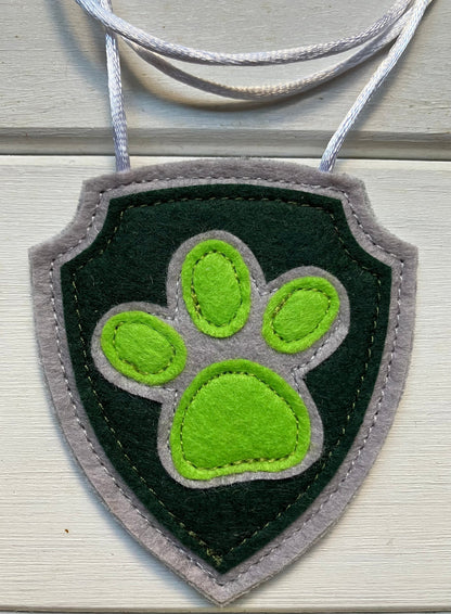 handmadeshield-shaped  felt badge with hanging string representing a paw patrol character