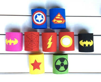 Superhero-themed wristbands with various symbols on a white wooden background 