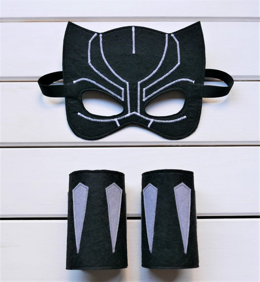 Handmade felt Black Panther mask and arm cuffs presented on a white wooden surface