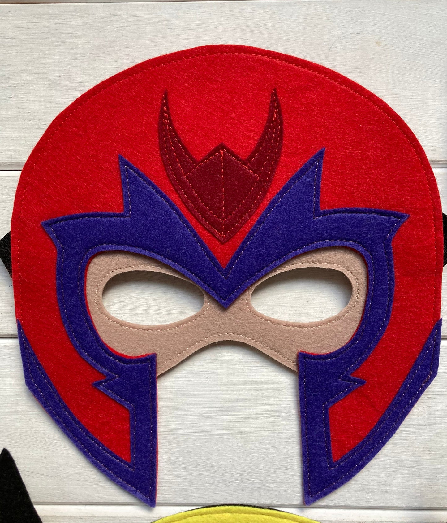 magneto Red and blue mask with a central emblem on a light wooden background