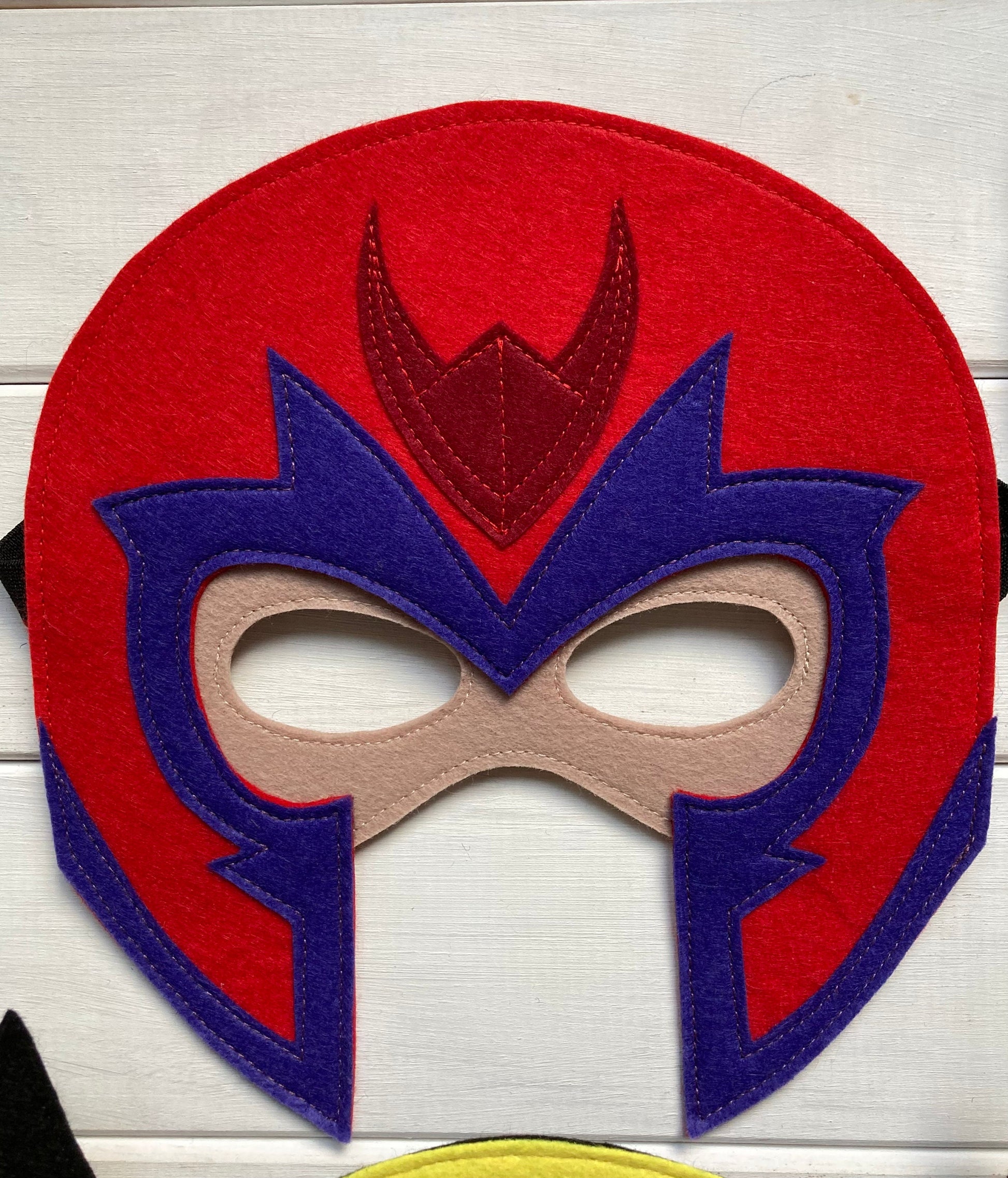 magneto Red and blue mask with a central emblem on a light wooden background