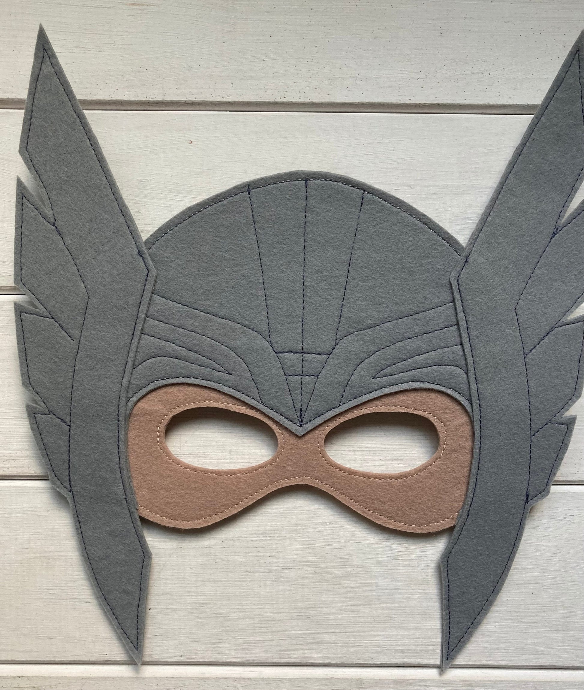 thor Gray superhero mask with brown accents on a light wooden background