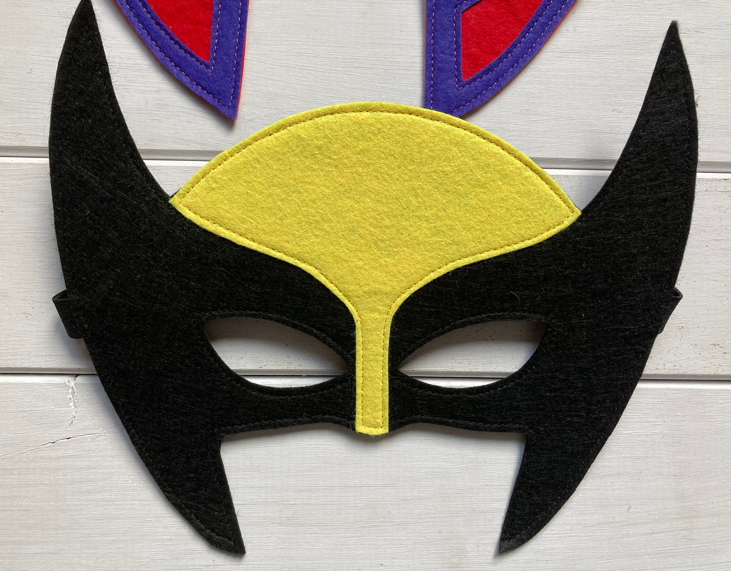 wolverine Mask with black horns and yellow center on a white wooden background