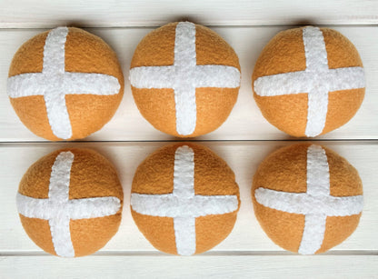 Six round bread rolls with white crosses, hot cross buns,  presented on a wooden surface
