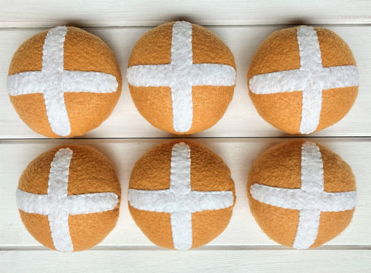 Six round bread rolls with white crosses, hot cross buns,  presented on a wooden surface