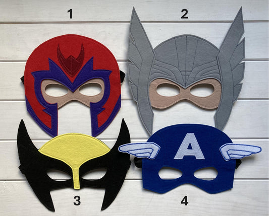 Four handmade felt superhero masks magneto captain america wolverine and thor presented on a wooden background