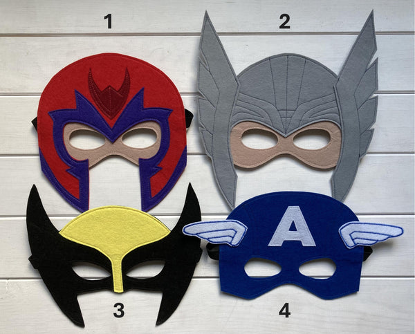 Four handmade felt superhero masks magneto captain america wolverine and thor presented on a wooden background