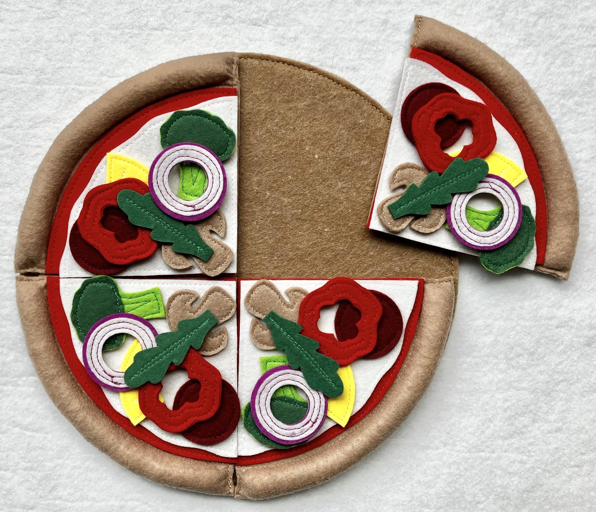 Handmade felt pizza toy with colorful toppings on a white background