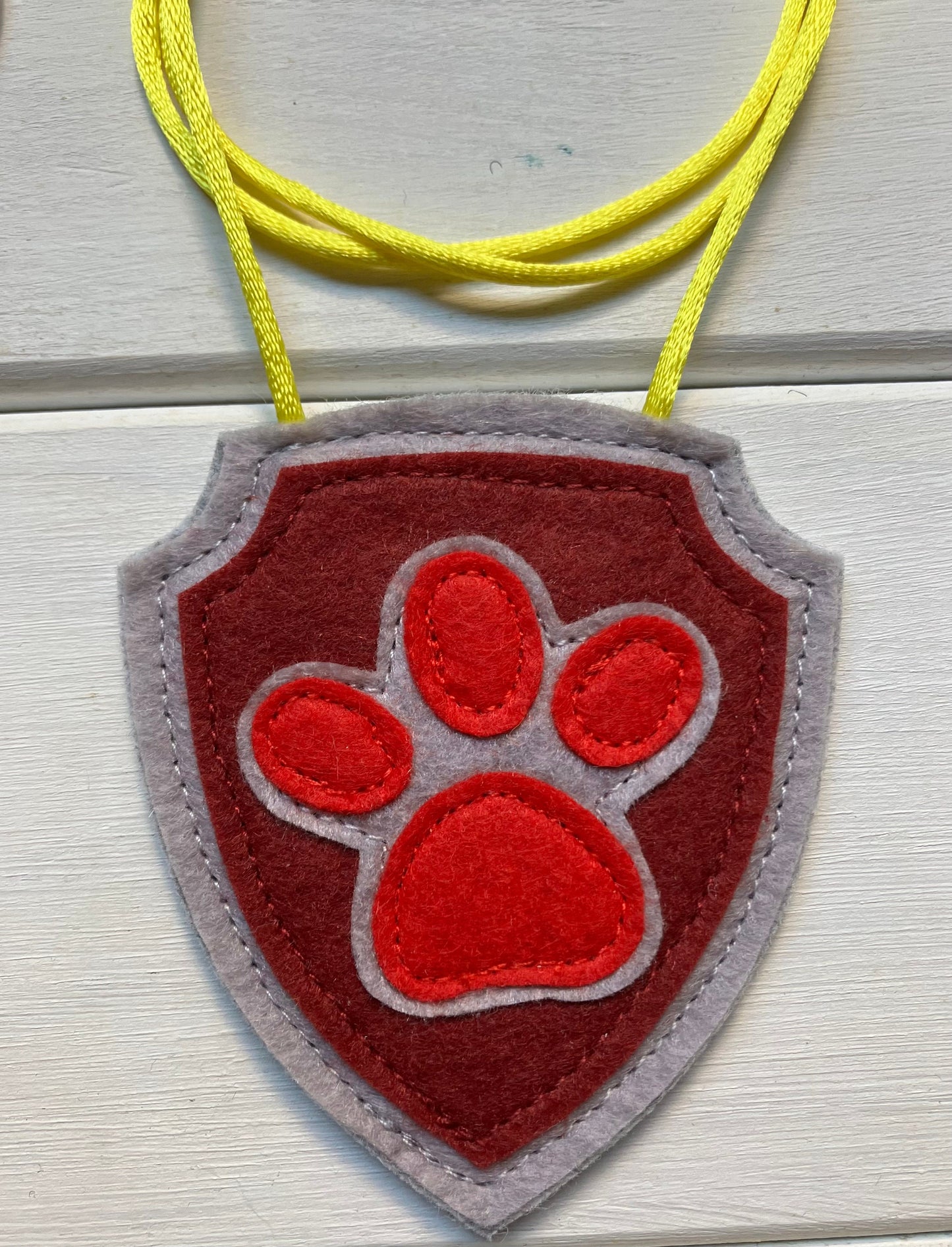 handmadeshield-shaped  felt badge with hanging string representing a paw patrol character